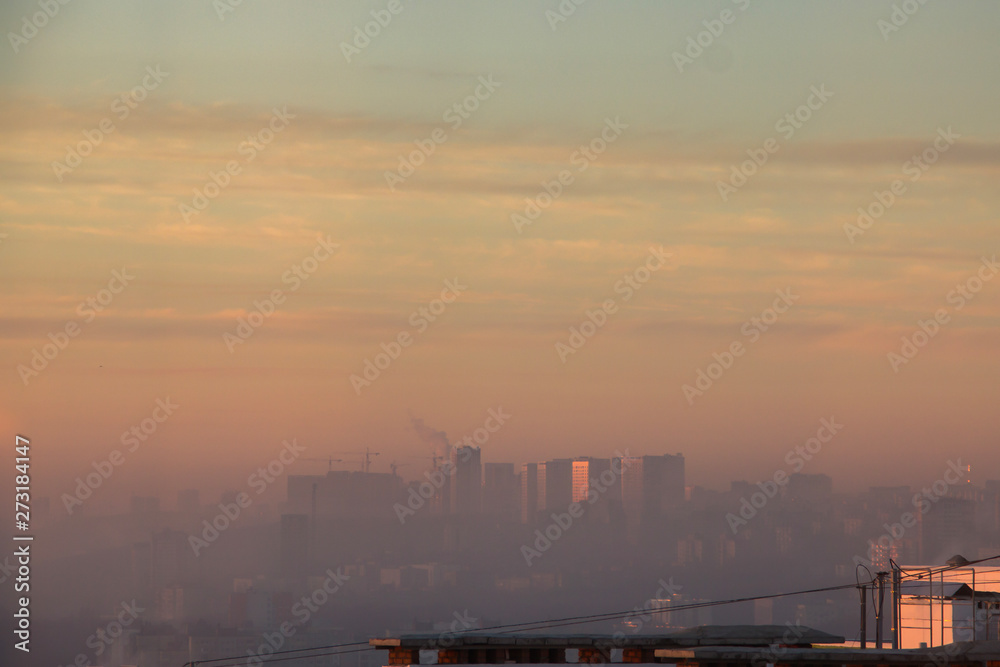Sunrise over factory at the industrial area. Orange light rays comes through morning fog and smoke from pipes. Power plant