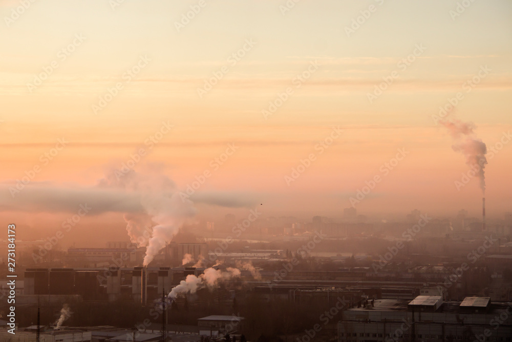 Sunrise over factory at the industrial area. Morning fog and smoke from pipes. Air pollution, ecology problems in big city