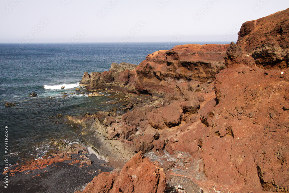 View on secluded lagoon surrounded by impressive rugged weathered cliffs in different colors - El Golfo, Lanzarote