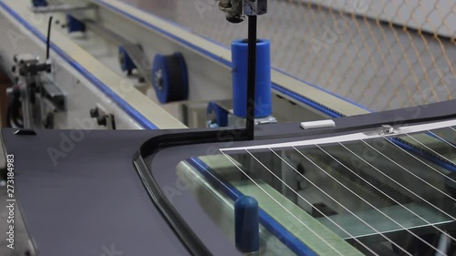 The robot, on the assembly line of the automobile plant, applies glue to the automotive glass.