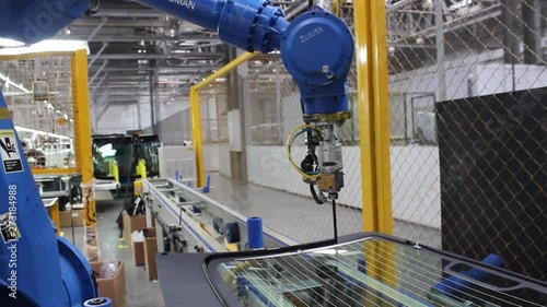 The robot, on the assembly line of the automobile plant, applies glue to the automotive glass.