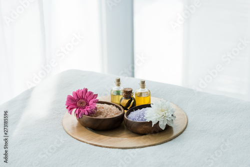 tray with bottles of oil, wooden bowls with sea salt and flowers in spa center