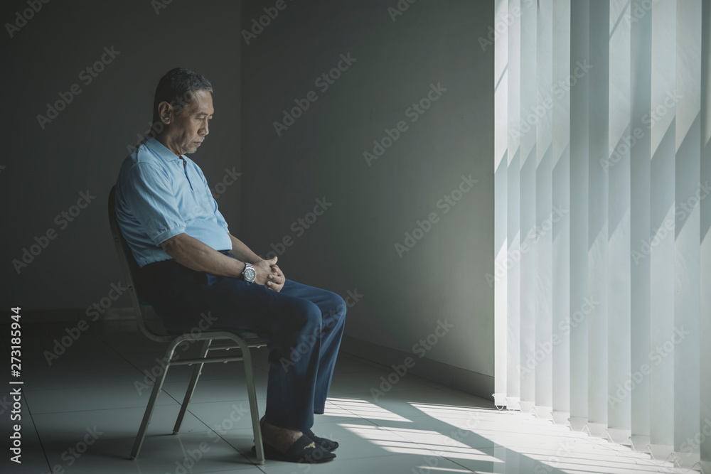 Lonely aged man looks sad near the window