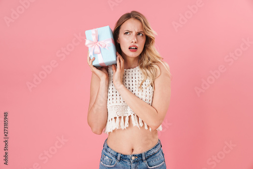 Woman posing isolated over pink wall background holding present box.