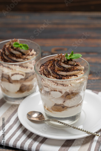 Classic tiramisu dessert in a glass on wooden background