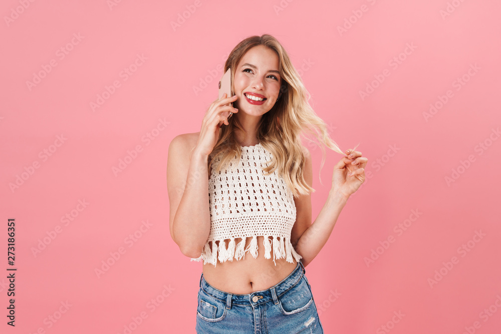 Happy young woman posing isolated over pink wall background talking by mobile phone. Happy young woman posing isolated over pink wall background talking by mobile phone.
