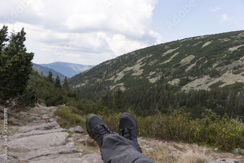 Hiker lies on the stones, with a view into the valley and the mountains