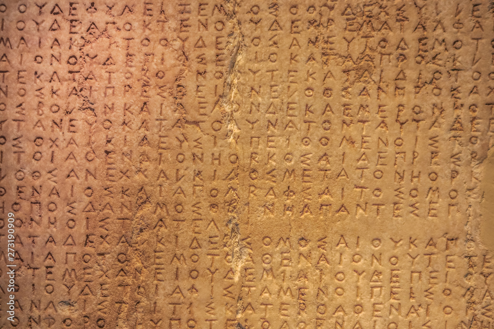Very textured old damaged Greek writing carved into a stone with cracks and damage and discoloration - grainy areas where damaged