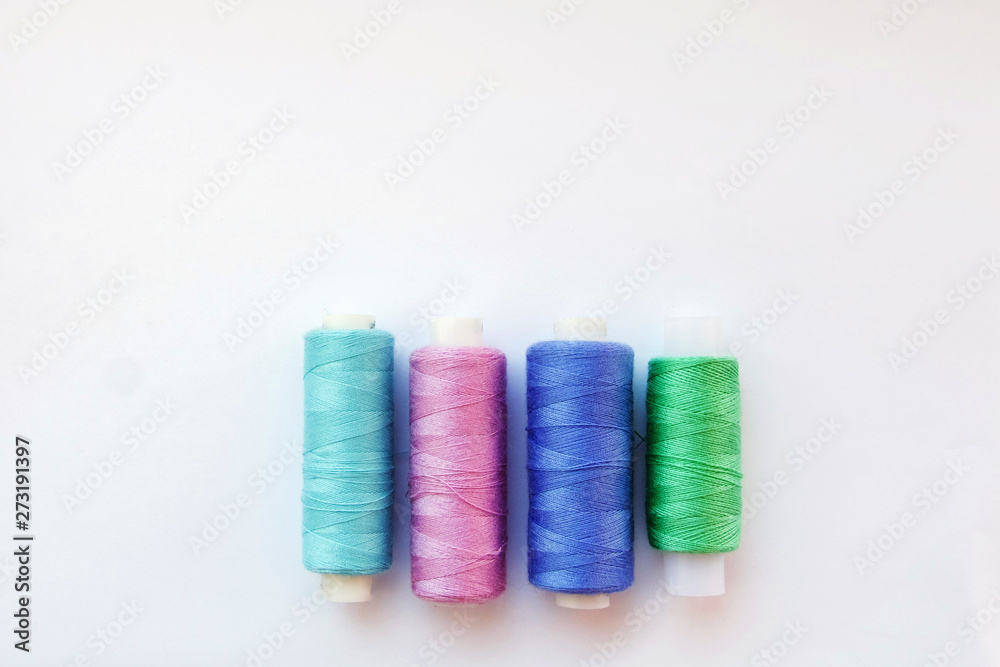 Multicolored thread coils on pink blue background. Sewing supplies and accessories for needlework, stitching, embroidery. space for text. flat lay, top view Multicolored thread coils on pink blue background. Sewing supplies and accessories for needlework, stitching, embroidery. space for text. flat lay, top view