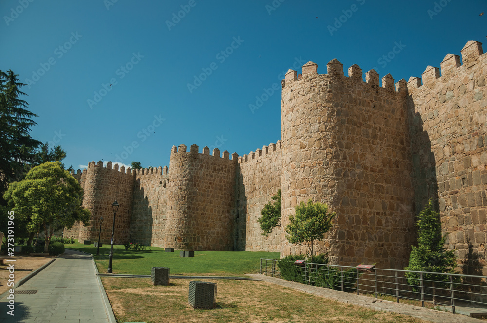 Several towers on the city wall and green garden at Avila