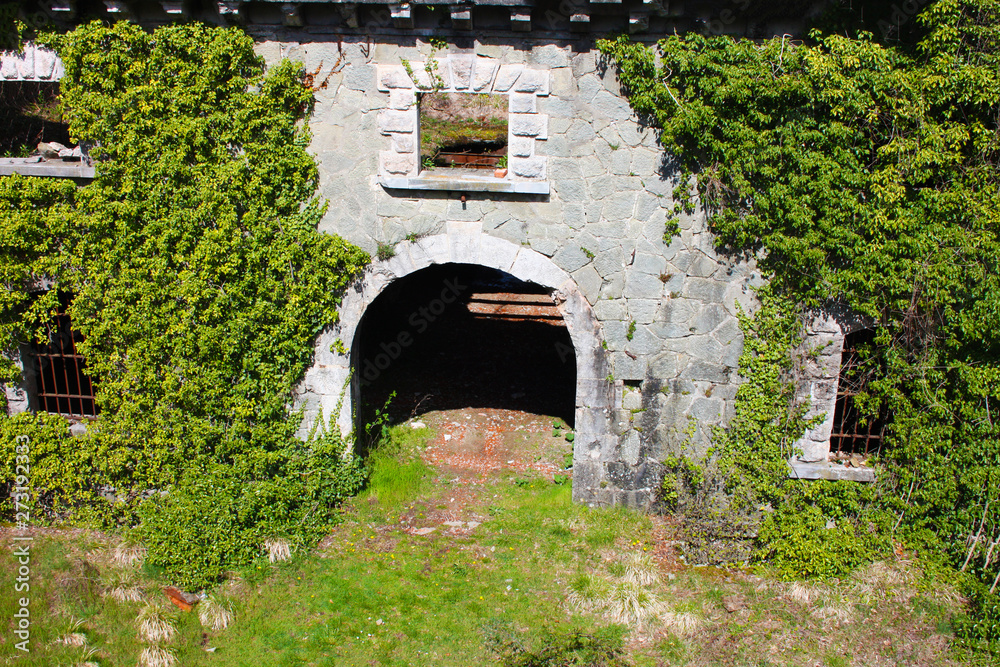 scary access portal, arched to enter the Fort Bastion of Fosdinovo, a fortress taken by nature and wild vegetation