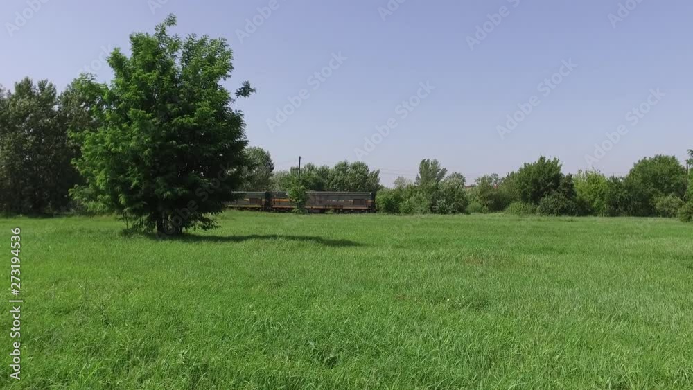 Two locomotive train driving slowly on the railway or railroad track through nature with green grass and trees Two locomotive train driving slowly on the railway or railroad track through nature with green grass and trees