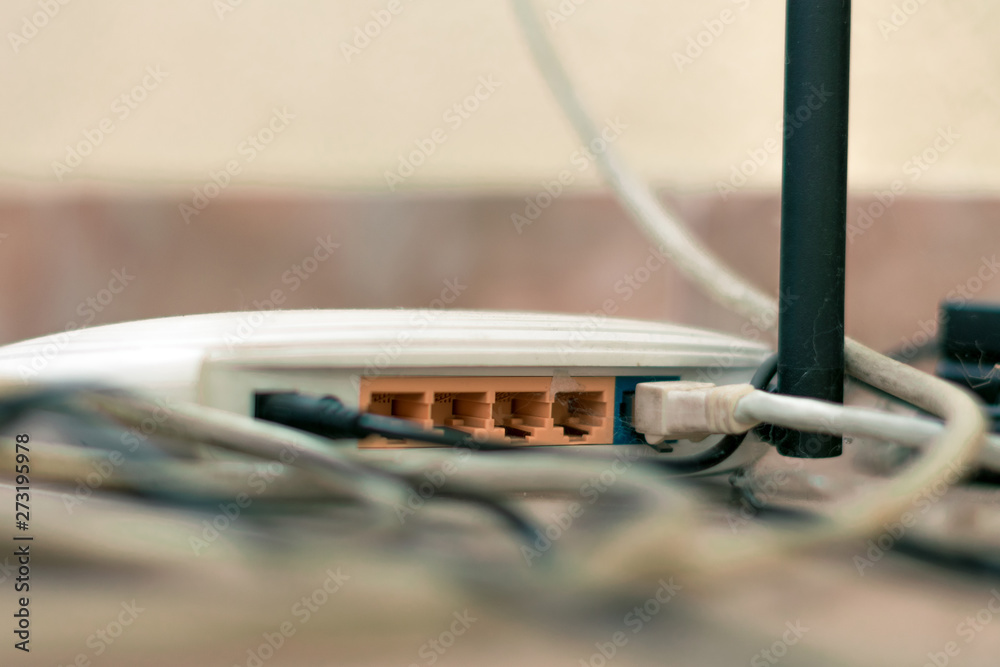 Old router among the wires and the web. Rear side of the router with connectors for connecting the Ethernet cable Old router among the wires and the web. Rear side of the router with connectors for connecting the Ethernet cable
