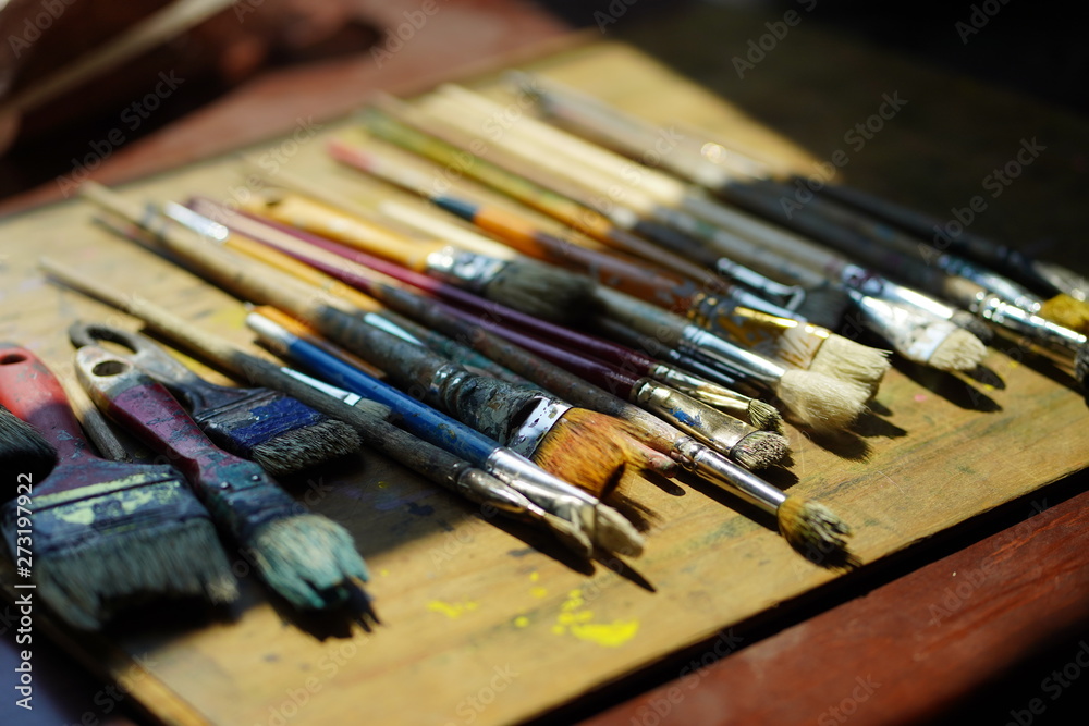 Artist brushes lie on a wooden board. The working environment of the artist for the background.