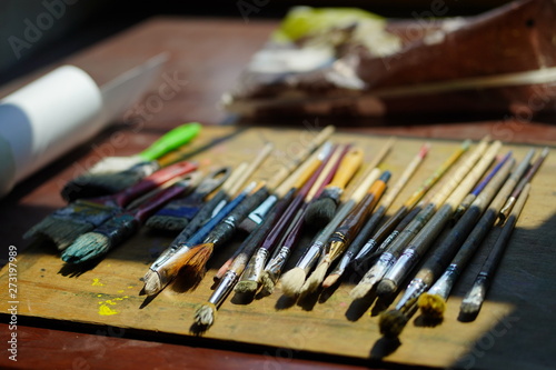 Artist brushes lie on a wooden board. The working environment of the artist for the background.