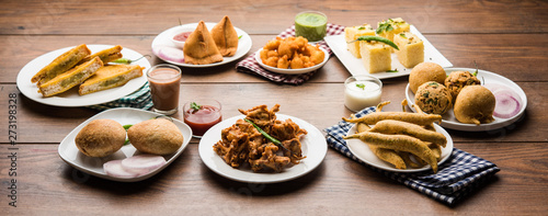 Indian Tea time snacks  in group includes Veg Samosa, Kachori/kachaudi, aloo bonda, khaman dhokla, bread, onion,chilli and moong pakora/pakoda/bhaji/bhajji/Bhajiya/bajji with sauces, selective focus