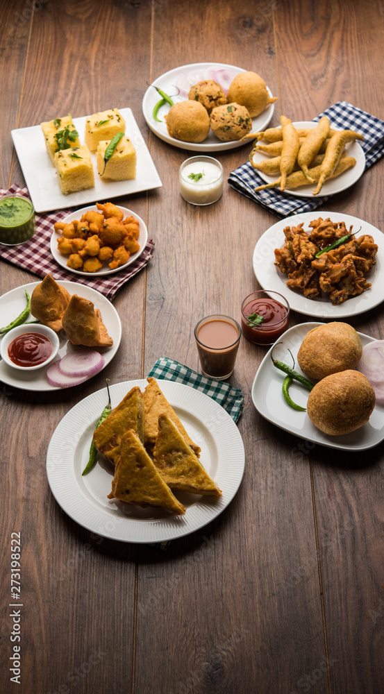 Indian Tea time snacks in group includes Veg Samosa, Kachori/kachaudi, aloo bonda, khaman dhokla, bread, onion,chilli and moong pakora/pakoda/bhaji/bhajji/Bhajiya/bajji with sauces, selective focus Indian Tea time snacks in group includes Veg Samosa, Kachori/kachaudi, aloo bonda, khaman dhokla, bread, onion,chilli and moong pakora/pakoda/bhaji/bhajji/Bhajiya/bajji with sauces, selective focus