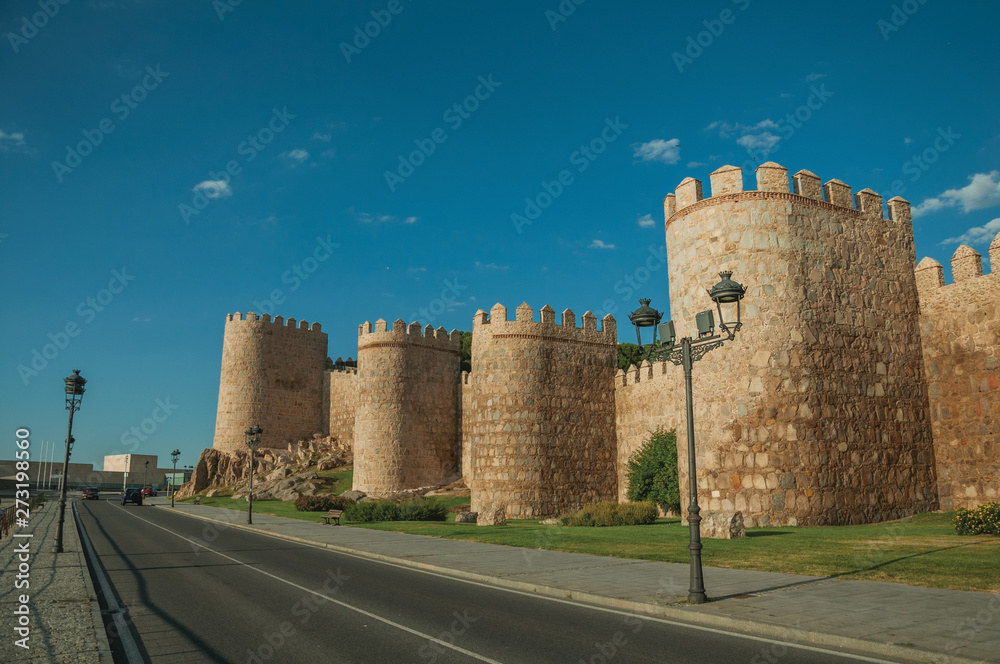 Street and light posts beside towers in the wall around Avila