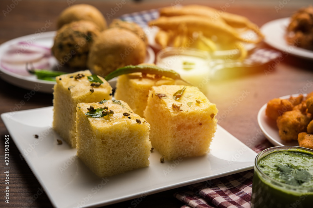 Indian Tea time snacks  in group includes Veg Samosa, Kachori/kachaudi, aloo bonda, khaman dhokla, bread, onion,chilli and moong pakora/pakoda/bhaji/bhajji/Bhajiya/bajji with sauces, selective focus