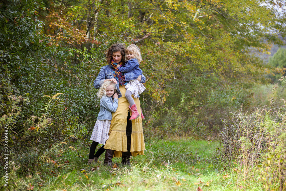 Mother with two children standing fixing child hair in wooded area Mother with two children standing fixing child hair in wooded area