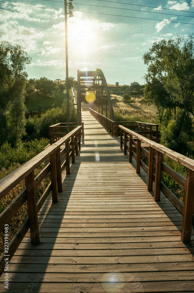 Obraz premium Sunbeam and wooden bridge over the Adaja River at Avila