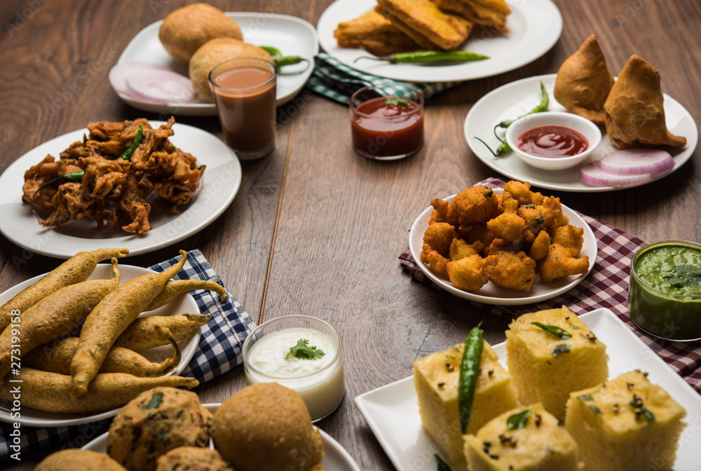Indian Tea time snacks in group includes Veg Samosa, Kachori/kachaudi, aloo bonda, khaman dhokla, bread, onion,chilli and moong pakora/pakoda/bhaji/bhajji/Bhajiya/bajji with sauces, selective focus Indian Tea time snacks in group includes Veg Samosa, Kachori/kachaudi, aloo bonda, khaman dhokla, bread, onion,chilli and moong pakora/pakoda/bhaji/bhajji/Bhajiya/bajji with sauces, selective focus
