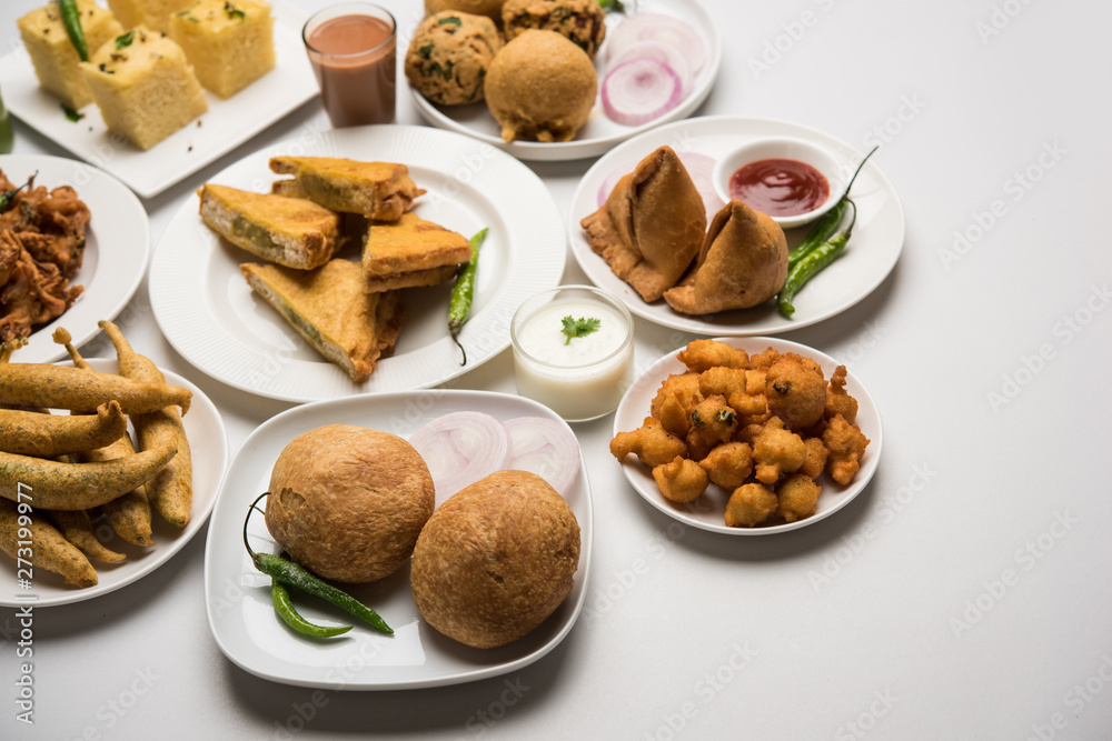 Indian Tea time snacks in group includes Veg Samosa, Kachori/kachaudi, aloo bonda, khaman dhokla, bread, onion,chilli and moong pakora/pakoda/bhaji/bhajji/Bhajiya/bajji with sauces, selective focus Indian Tea time snacks in group includes Veg Samosa, Kachori/kachaudi, aloo bonda, khaman dhokla, bread, onion,chilli and moong pakora/pakoda/bhaji/bhajji/Bhajiya/bajji with sauces, selective focus