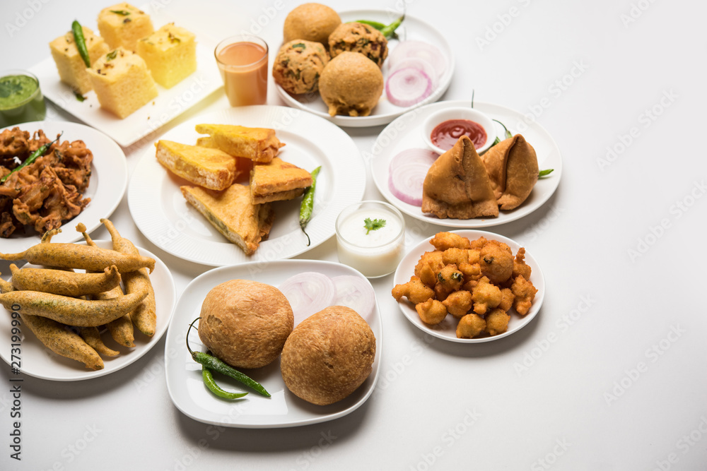 Indian Tea time snacks in group includes Veg Samosa, Kachori/kachaudi, aloo bonda, khaman dhokla, bread, onion,chilli and moong pakora/pakoda/bhaji/bhajji/Bhajiya/bajji with sauces, selective focus Indian Tea time snacks in group includes Veg Samosa, Kachori/kachaudi, aloo bonda, khaman dhokla, bread, onion,chilli and moong pakora/pakoda/bhaji/bhajji/Bhajiya/bajji with sauces, selective focus