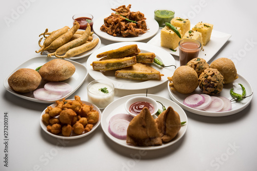 Indian Tea time snacks in group includes Veg Samosa, Kachori/kachaudi, aloo bonda, khaman dhokla, bread, onion,chilli and moong pakora/pakoda/bhaji/bhajji/Bhajiya/bajji with sauces, selective focus
