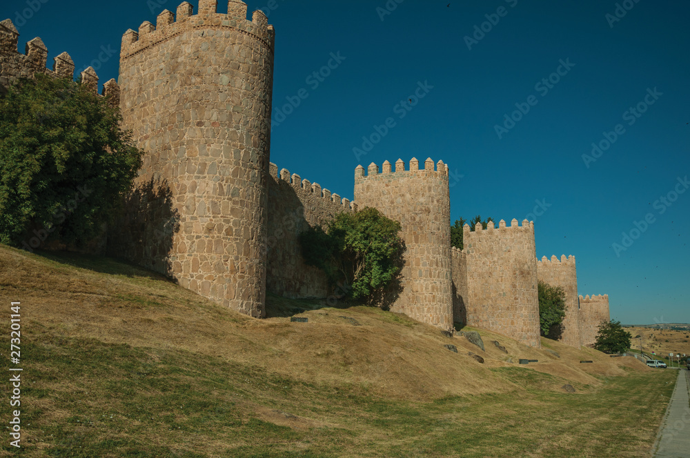 Stone towers on the large city wall and green lawn at Avila