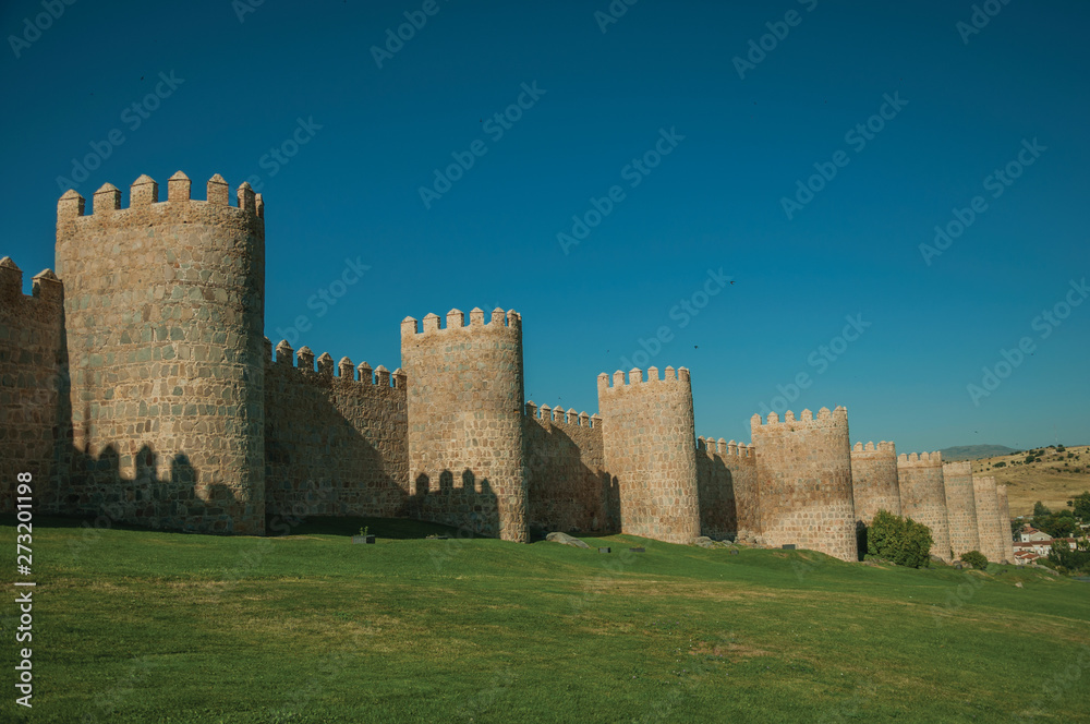 Stone towers on the large city wall and green lawn at Avila
