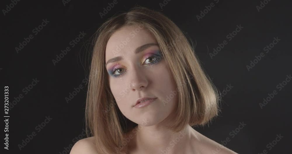 Closeup shoot of young pretty caucasian short haired female with cute glitter makeup smiling happily looking at camera with background isolated on black Closeup shoot of young pretty caucasian short haired female with cute glitter makeup smiling happily looking at camera with background isolated on black