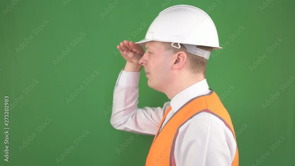 Male chief foreman in a protective helmet and signal vest looks into the distance on a construction site, green background, hromakey Male chief foreman in a protective helmet and signal vest looks into the distance on a construction site, green background, hromakey