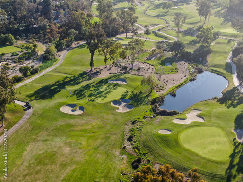 Aerial top view of a green golf course during sunny day. South California.