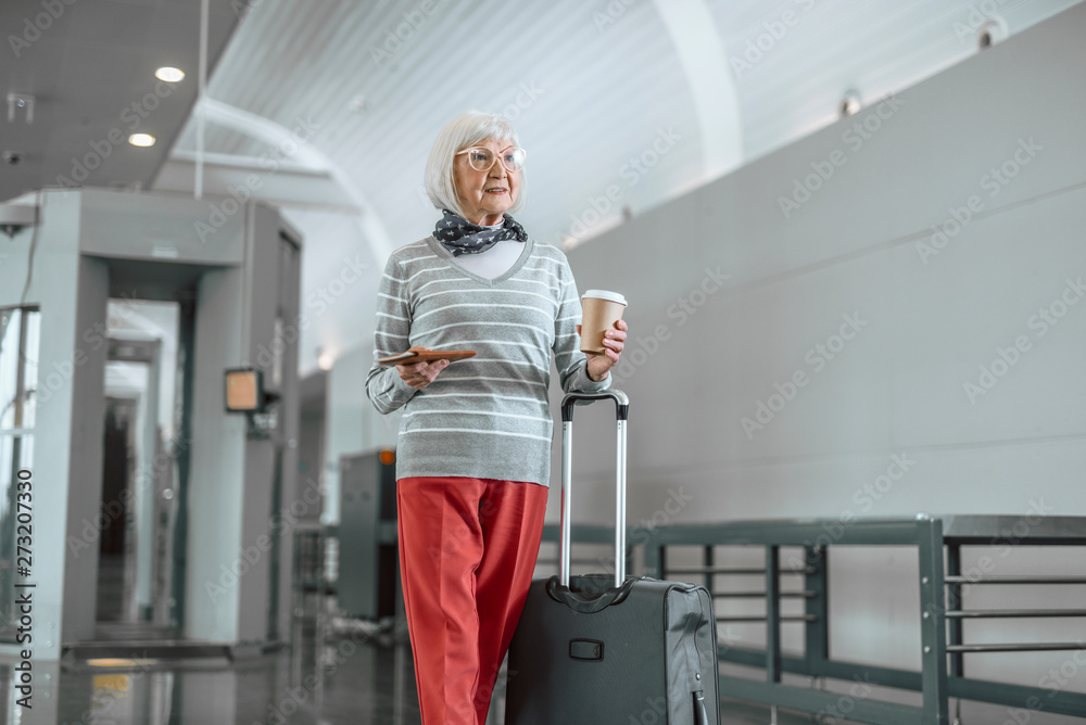 Cheerful mature lady with luggage enjoying travel