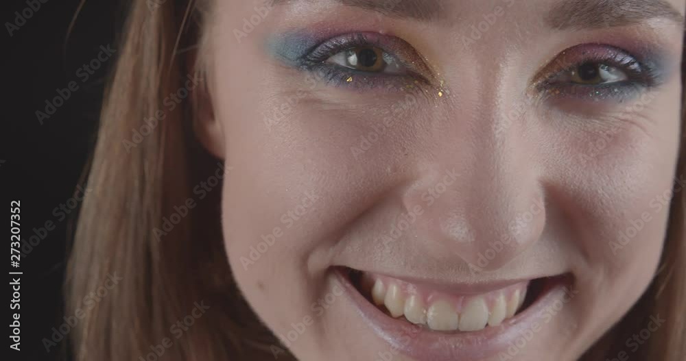 Closeup portrait of young charming caucasian short haired female face with cute glitter makeup looking at camera smiling with background isolated on black Closeup portrait of young charming caucasian short haired female face with cute glitter makeup looking at camera smiling with background isolated on black
