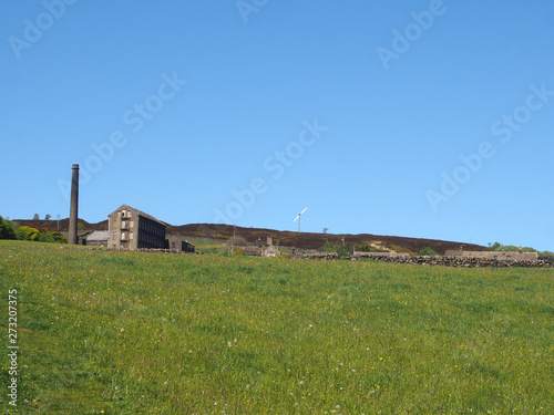 a bright green grass meadow covered in on a hillside with the old mill chimney and stone house houses at old town near hebden bridge west yorkshire © Philip J Openshaw 