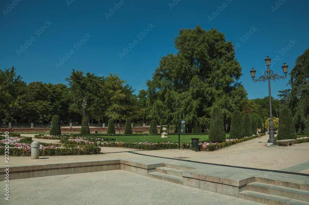 Pedestrian promenade with trees and streetlights in a park of Madrid