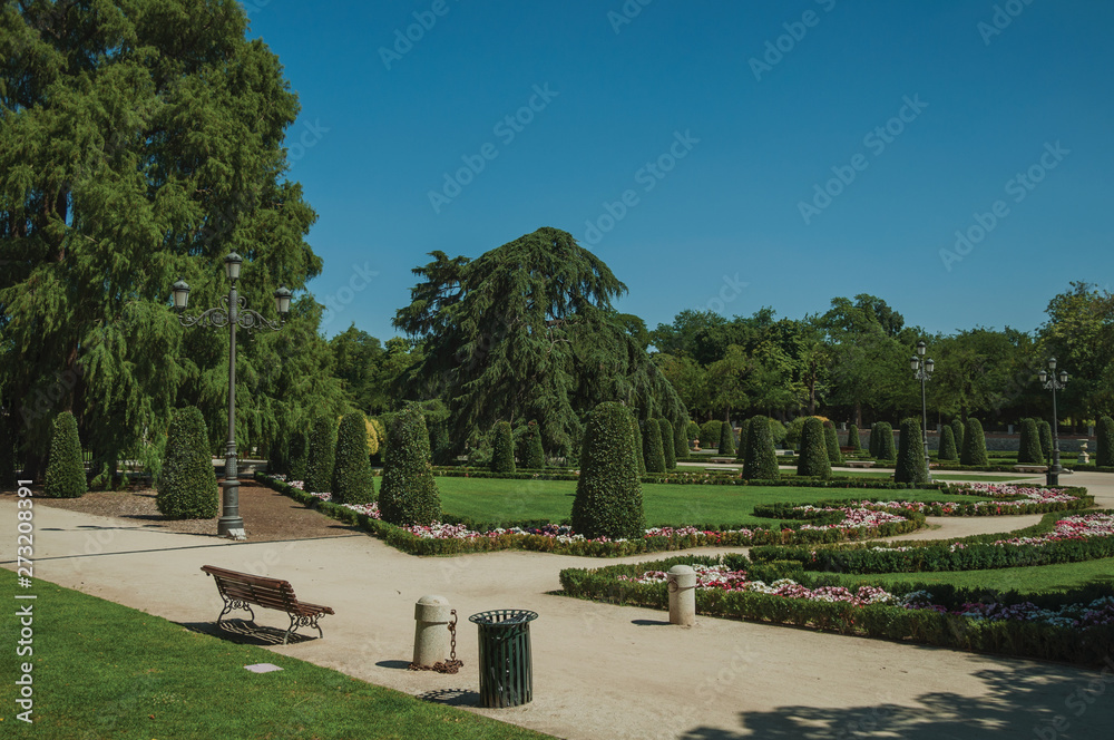 Pathway on gardens with trees and streetlights in a park of Madrid