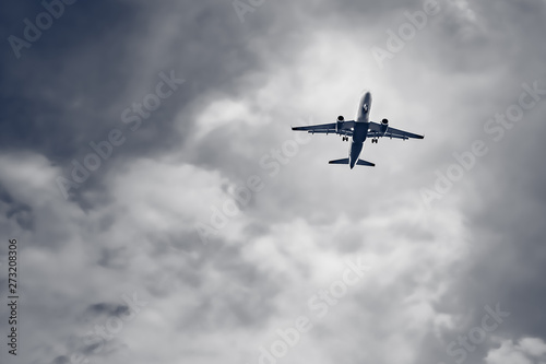 Passenger airplane flying on storm dark clouds background.