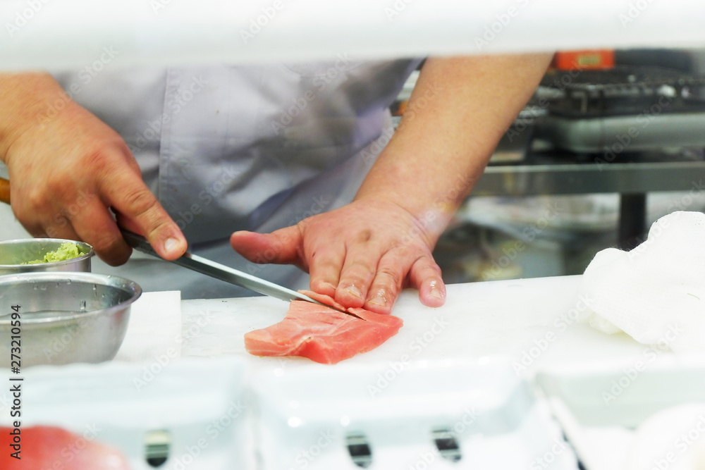 Japanese Chef Preparing Sushi.  He prepares sushi, known as nigiri, for dinner. This traditional Japanese food is being prepared on a wooden platter. stock photo