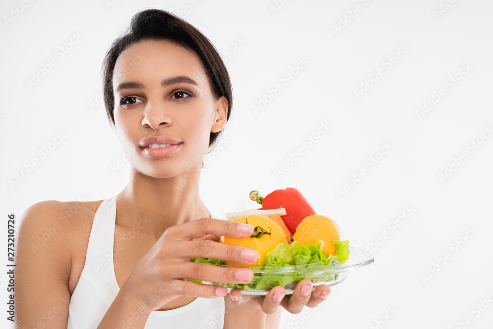 Smiling slender lady holding plate with vegetables Smiling slender lady holding plate with vegetables