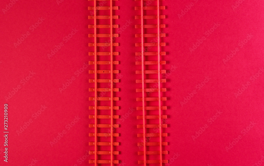 Toy railway rails on a red background. Top view