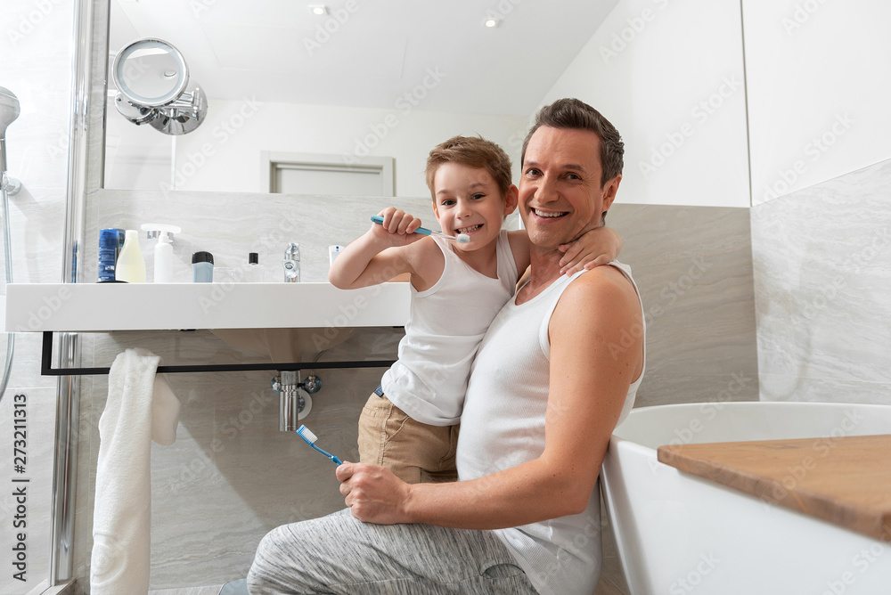 Fototapeta premium Father and son doing morning procedure in bathroom