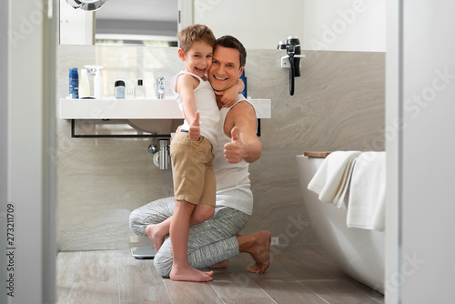 Smiling father and son staying in bathroom at home