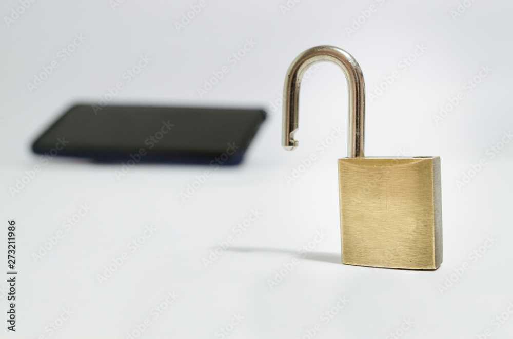 Conceptual photo security on mobile phones. A open padlock in the foreground and a cell phone in the background on a white background. Conceptual photo security on mobile phones. A open padlock in the foreground and a cell phone in the background on a white background.