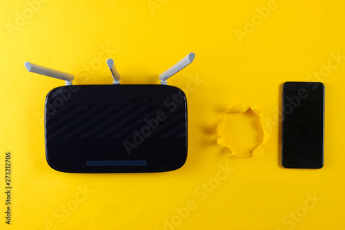 Wi-Fi router and smartphone on a yellow background with torn hole