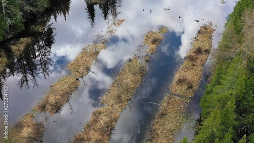 Flying over the remenants of an abandoned hatchery with clouds reflecting in the water Close up AERIAL photo