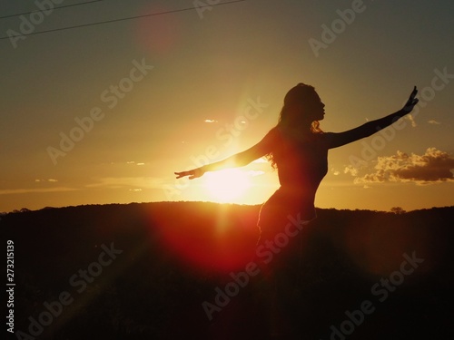 woman's silhouette practicing yoga at sunset