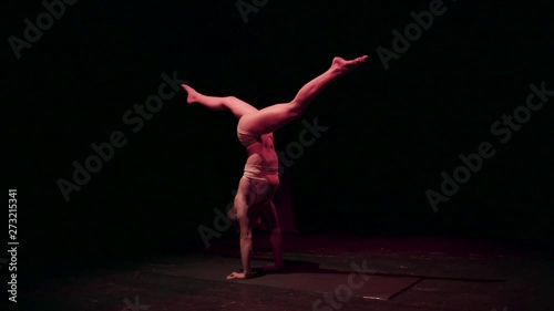 Female contortionist circus performer performing routine in dark studio photo